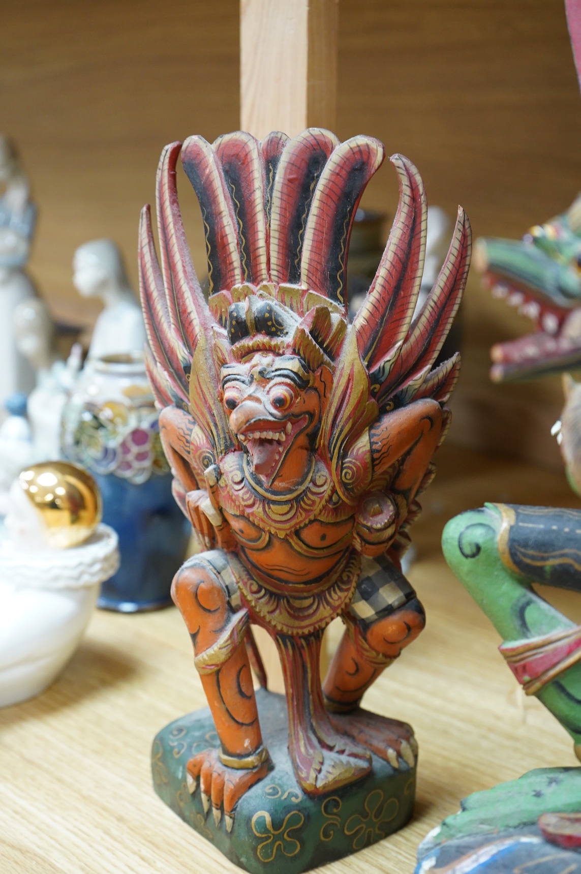 A Balinese painted and carved wood sculpture of Garuda, together with a smaller similar carving, largest 46cm high